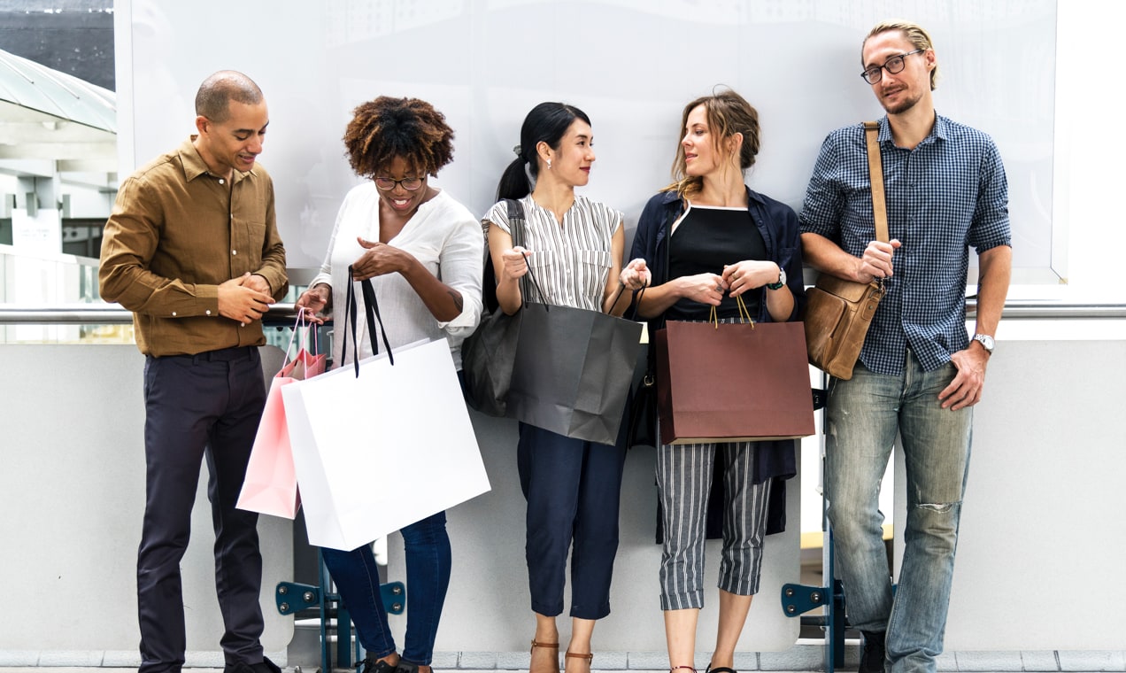 Group of men and women standing with shopping bags.