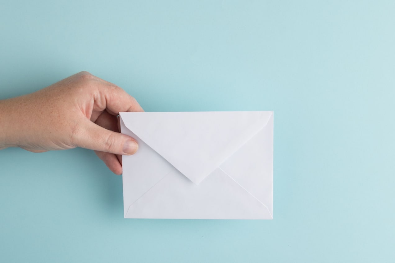 hand holding a white envelope on top of a blue background