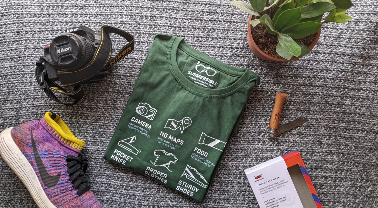 green t-shirt surrounded by hiking items