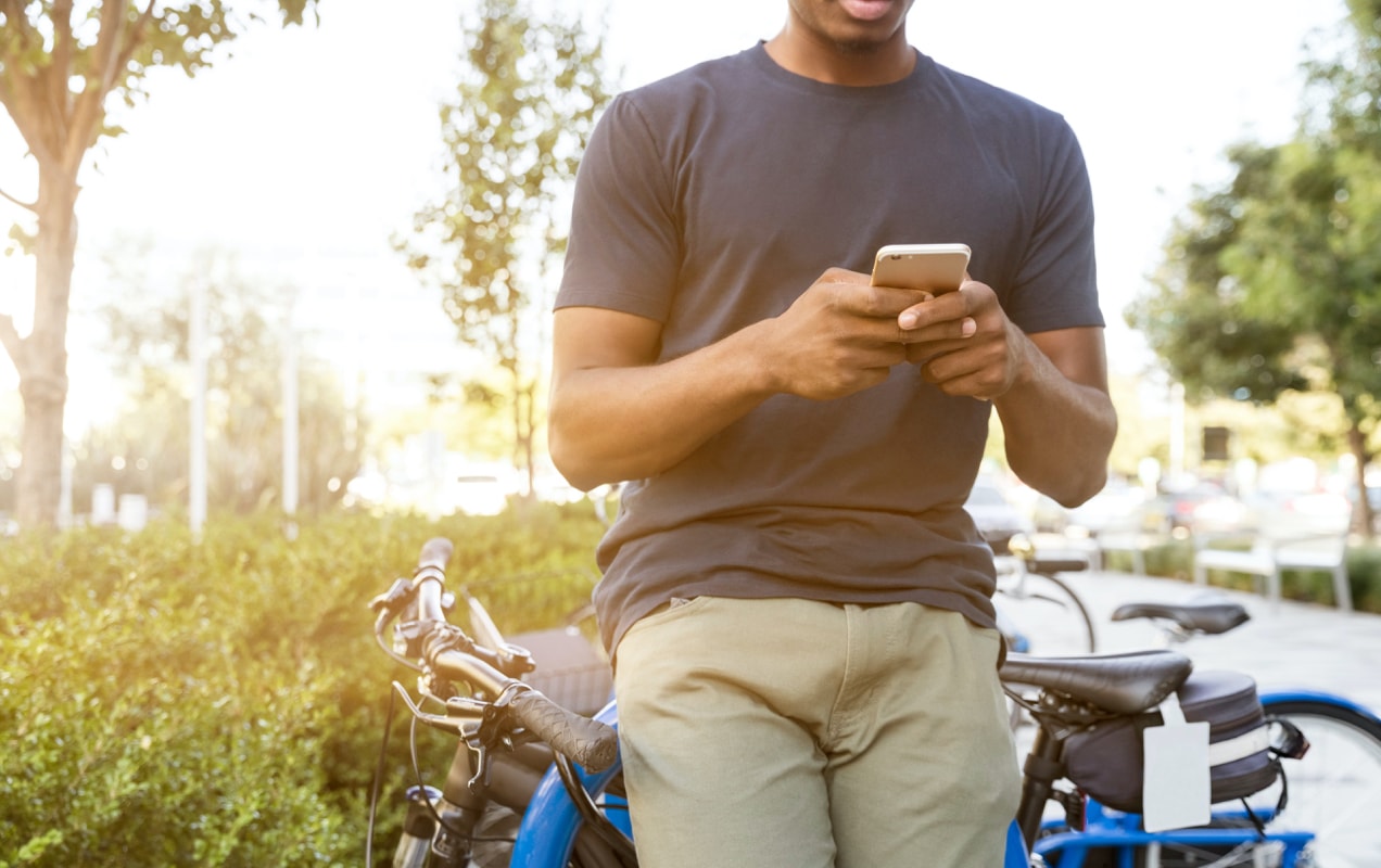 un homme regarde son téléphone en faisant du vélo