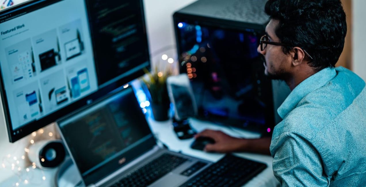 man working at a desk with multiple screens