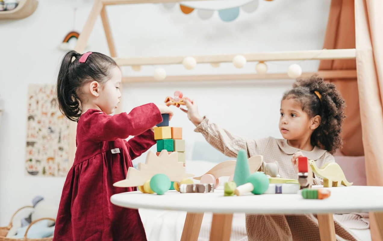 two children playing with wooden toys at a table