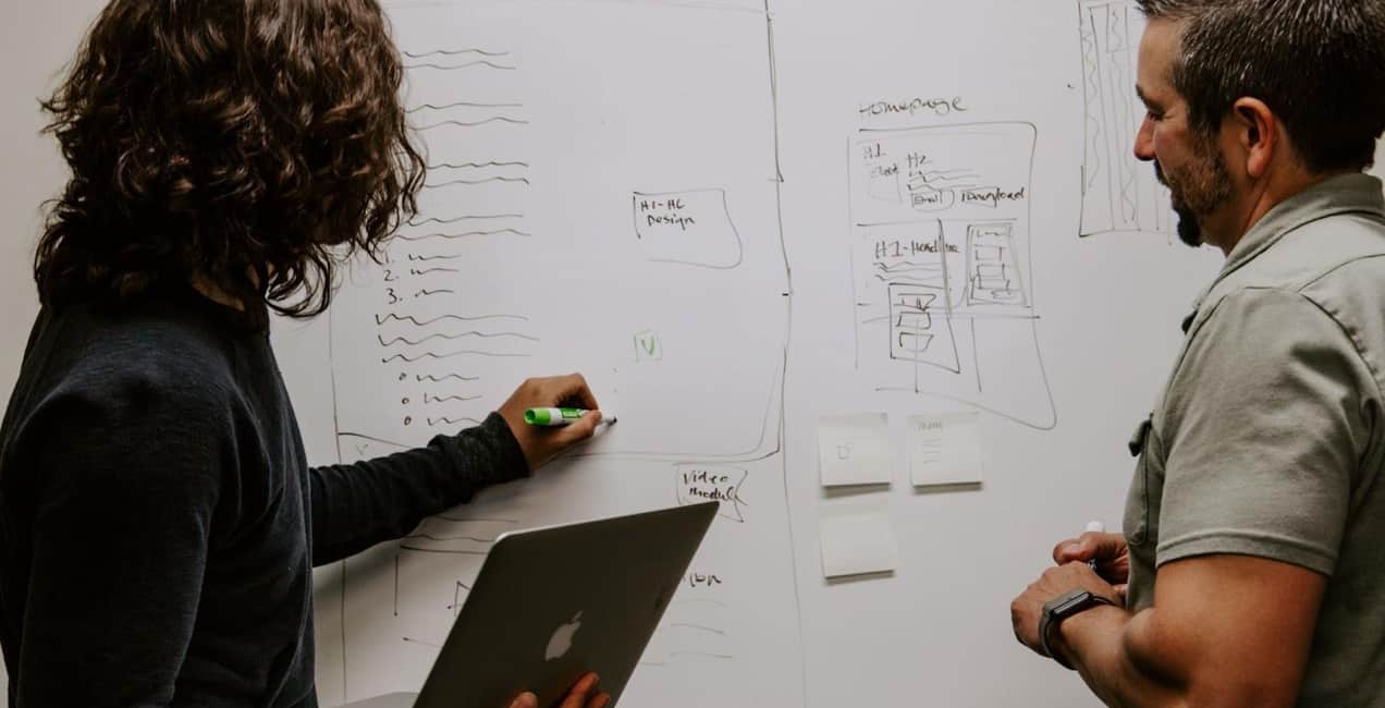 two people working at a whiteboard