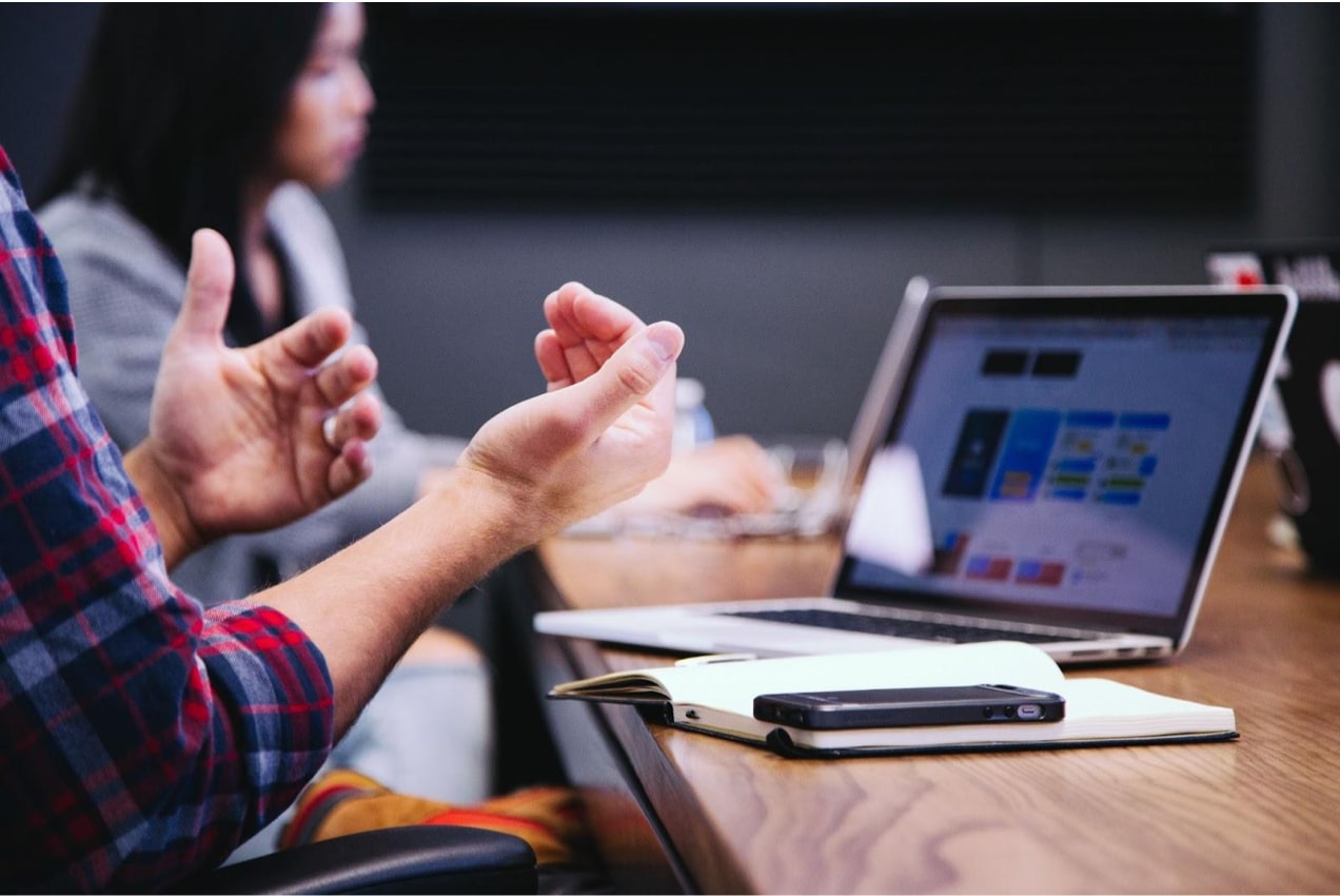 man discussing something with a colleague in front of a laptop