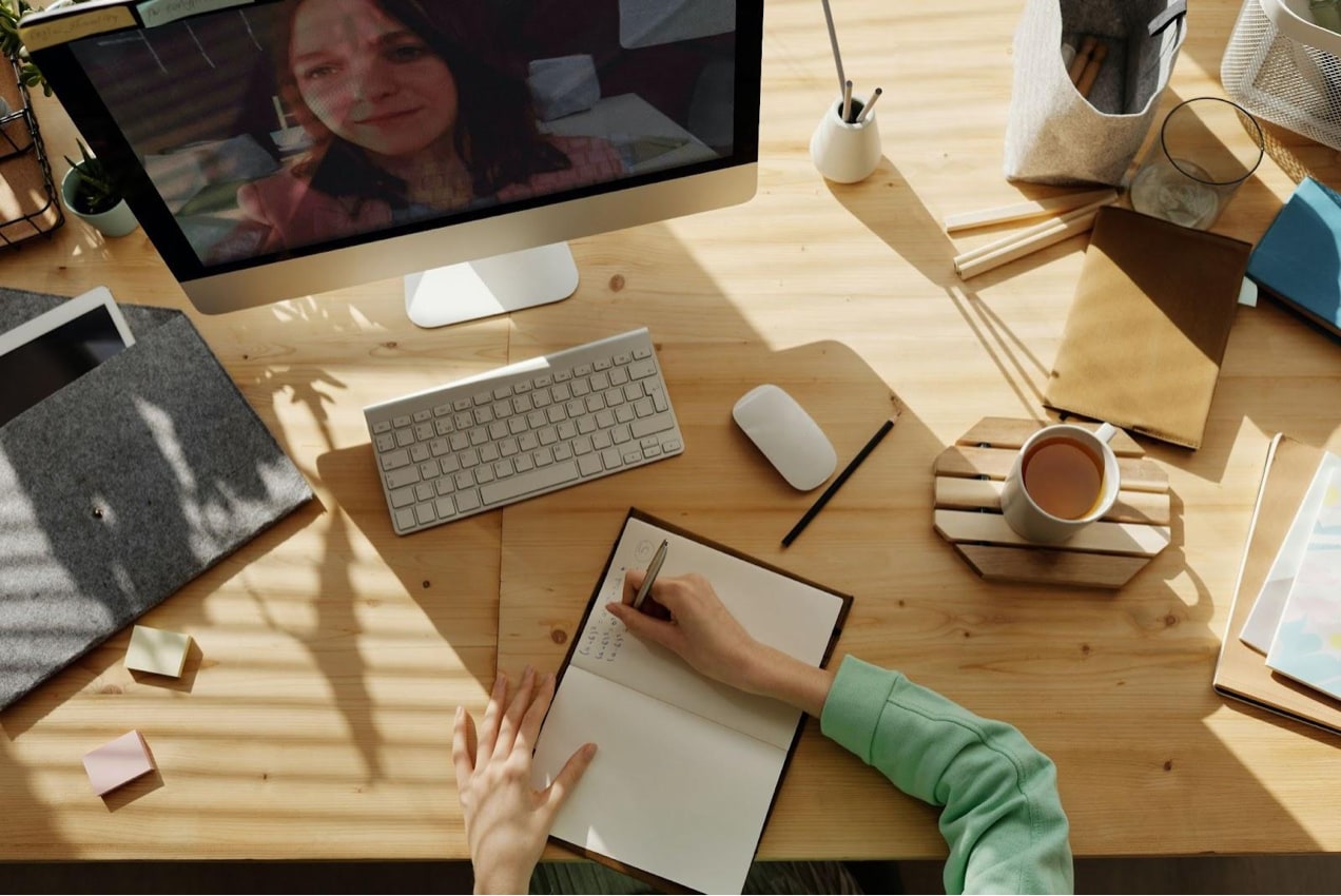 woman writing in a notebook in front of a video course