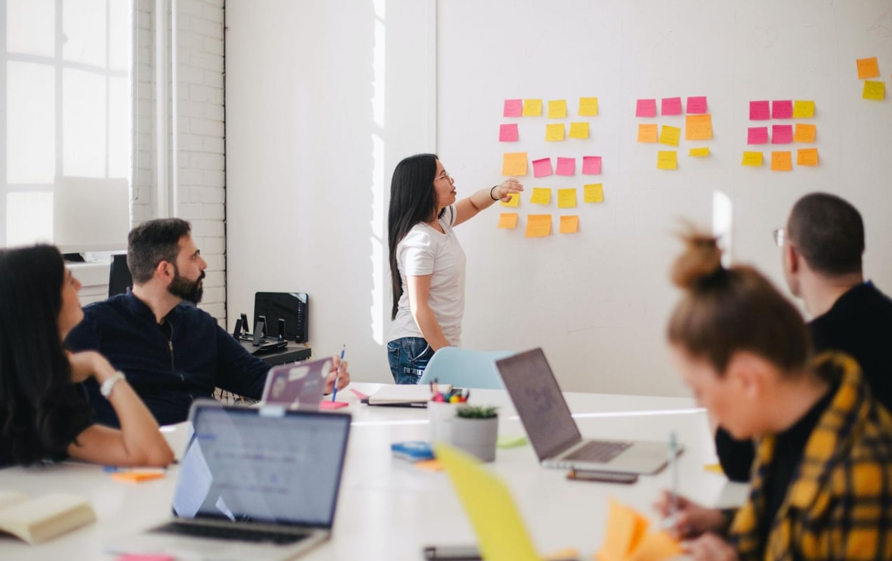 team meeting around a board with sticky notes