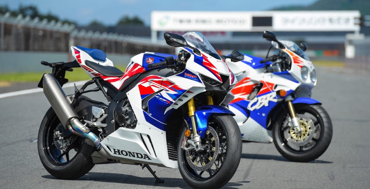 two blue, white, and red Honda motorcycles on a track