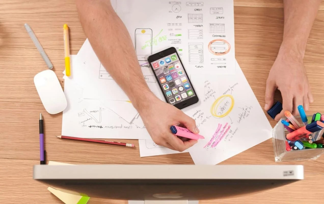 someone working at a desk, with mockups and notes in front of him, using a highlighter 