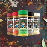 Five jars of Dan-O’s seasoning blends against a background of loose spices.